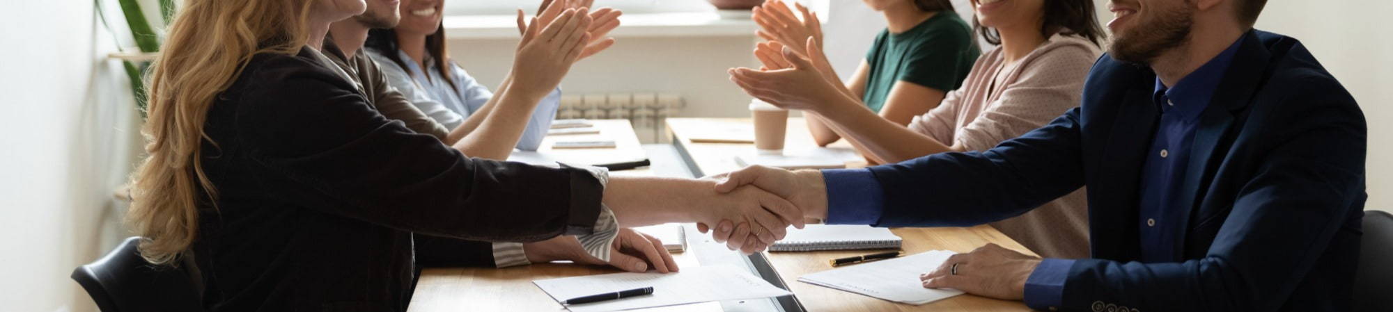 A woman and a man shake hands during business meeting cropped