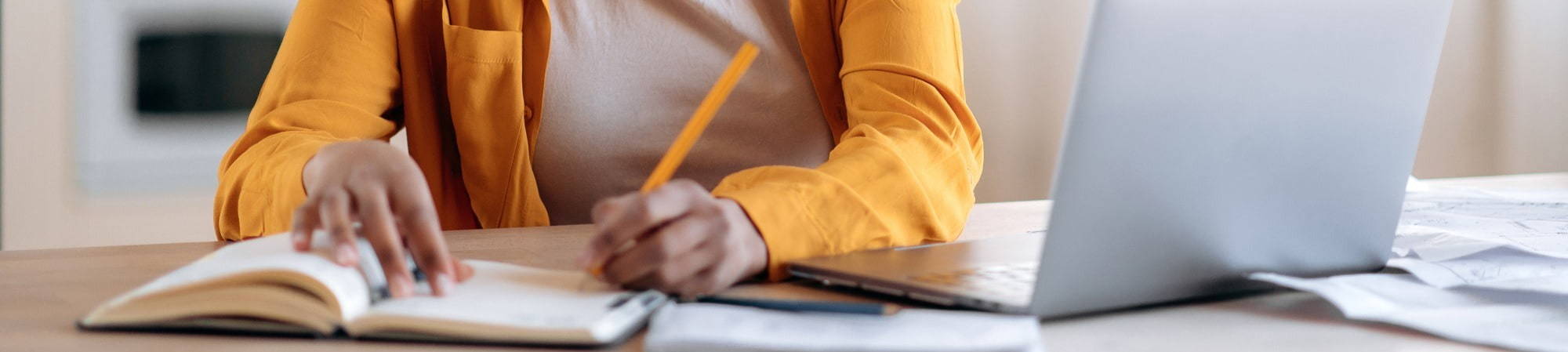 Woman taking notes beside laptop